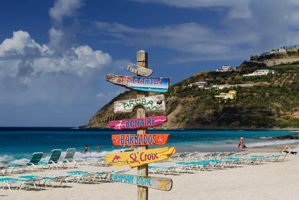 Colorful beach signpost with Caribbean destinations and Zion National Park.
