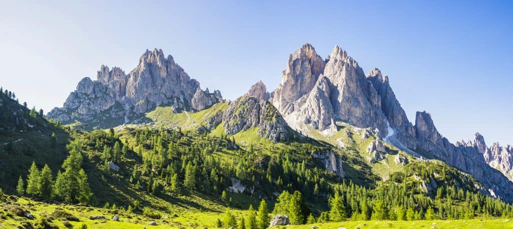 Scenic mountain landscape with rugged peaks and lush green forest.