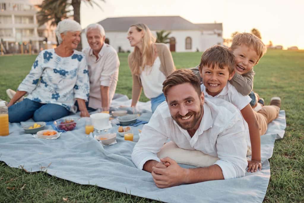 Family enjoying a picnic on a sunny day in the park with children and grandparents.
